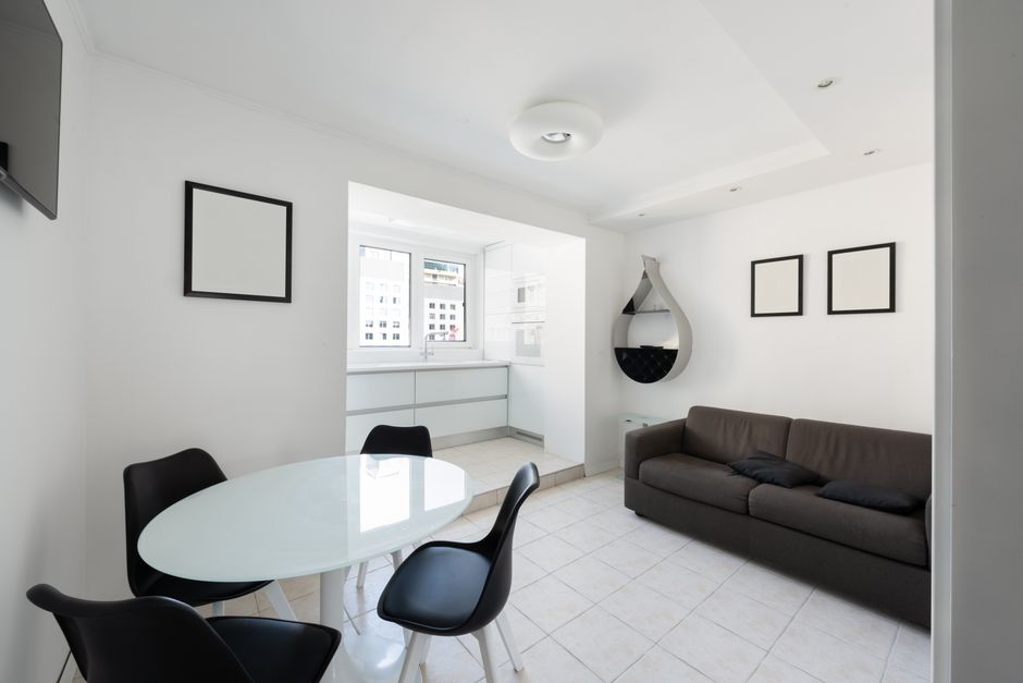 Interior of modern light house with glass table near chairs and couch with pillows near paintings and shelves on wall near entrance to kitchen with counter with window What is a ceiling paint and its specifics